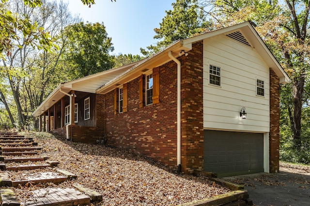 view of side of property featuring a garage, driveway, a porch, and brick siding