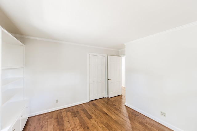 spare room with crown molding, baseboards, and wood finished floors