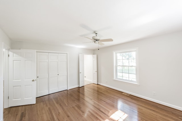 unfurnished bedroom with wood finished floors, visible vents, and baseboards