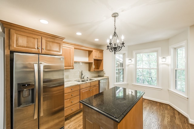 kitchen with stainless steel appliances, a sink, dark stone countertops, and a kitchen island