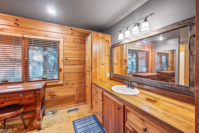 bathroom with hardwood / wood-style floors, vanity, and wood walls