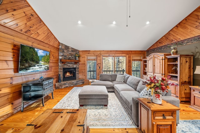 living room with a fireplace, light wood-type flooring, high vaulted ceiling, and wooden walls