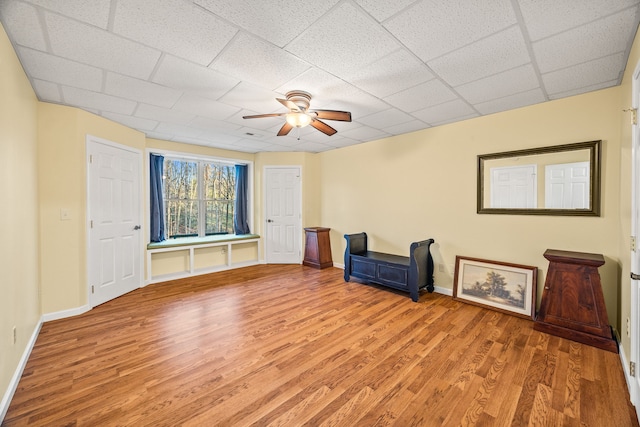 interior space featuring ceiling fan, a drop ceiling, and light hardwood / wood-style floors