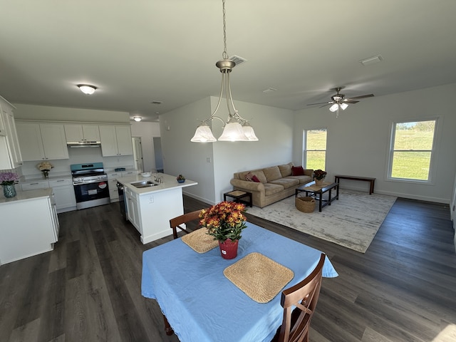 dining area with dark hardwood / wood-style floors, sink, and ceiling fan with notable chandelier