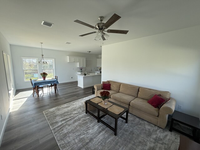 living room featuring ceiling fan with notable chandelier and dark hardwood / wood-style flooring