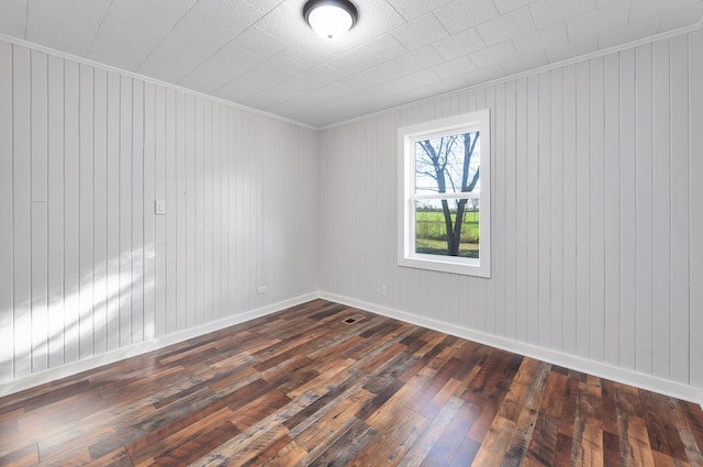 empty room with ornamental molding, dark wood-type flooring, and wood walls