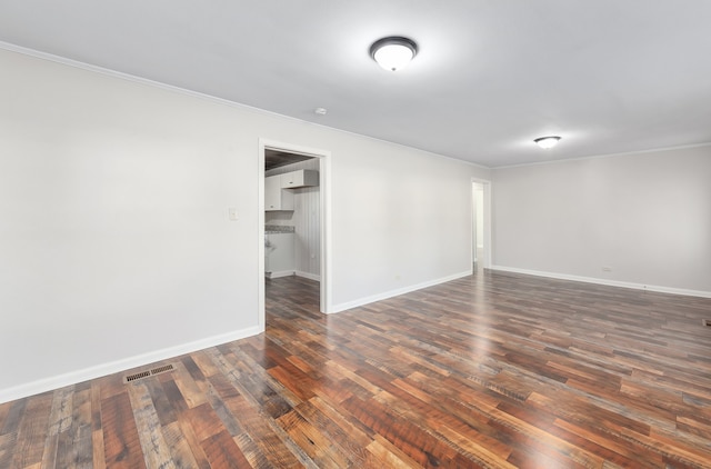 empty room featuring crown molding and dark hardwood / wood-style flooring