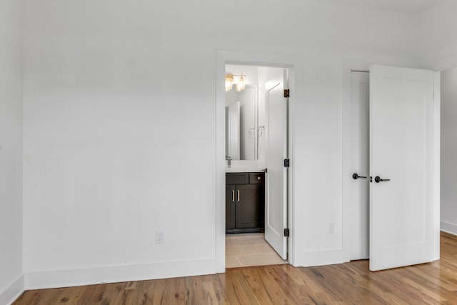 unfurnished bedroom featuring light wood-type flooring and ensuite bath