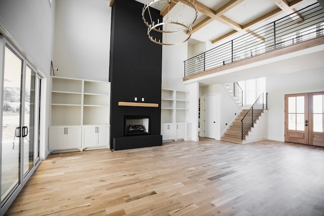 unfurnished living room featuring a high ceiling, coffered ceiling, french doors, light hardwood / wood-style flooring, and a fireplace