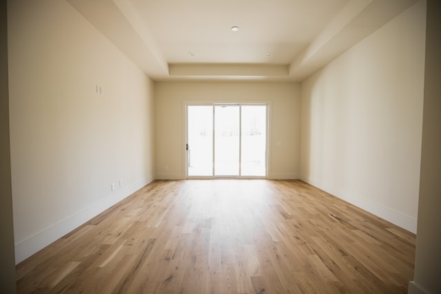 unfurnished room with a tray ceiling and light hardwood / wood-style floors