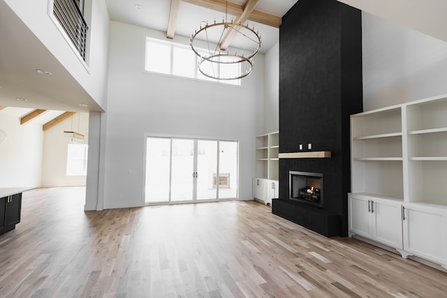 unfurnished living room featuring plenty of natural light, beam ceiling, and high vaulted ceiling