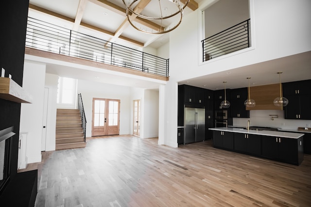 living room featuring french doors, sink, hardwood / wood-style flooring, beamed ceiling, and a high ceiling