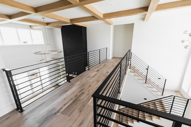 stairway featuring a notable chandelier, beam ceiling, wood-type flooring, and coffered ceiling