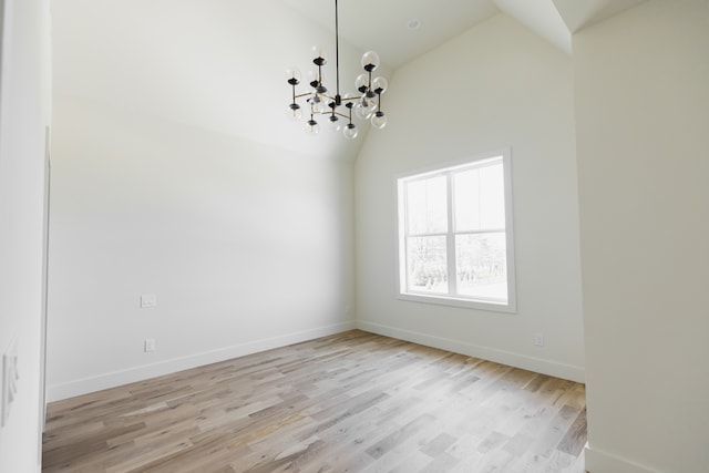 unfurnished room with a chandelier, high vaulted ceiling, and light hardwood / wood-style floors