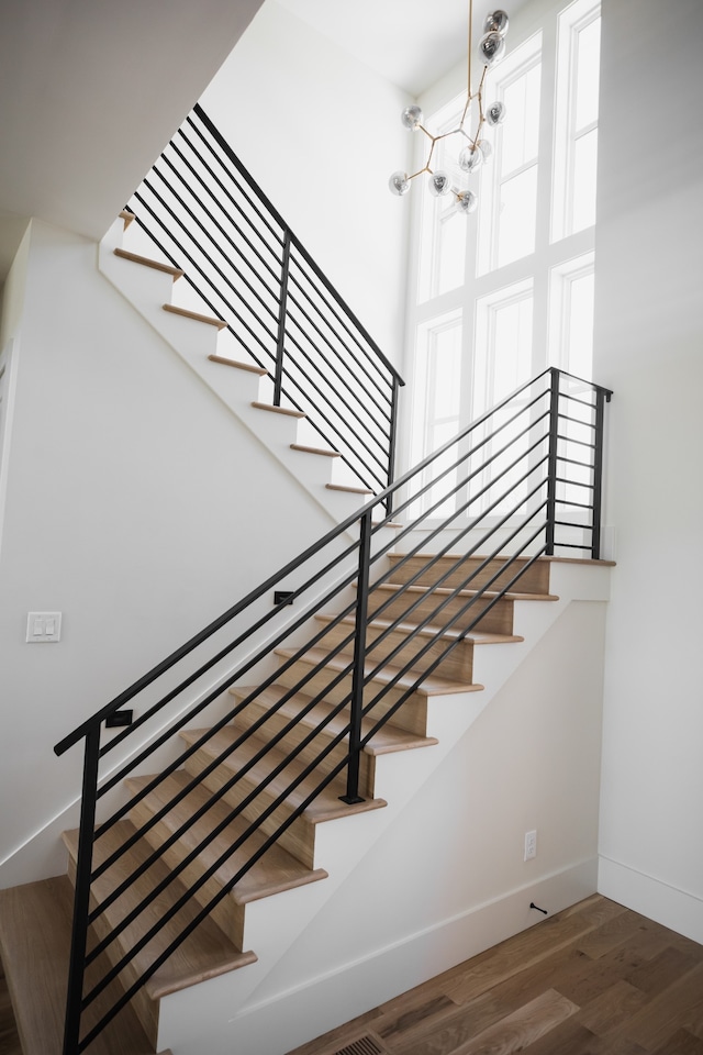 stairway with a chandelier and hardwood / wood-style floors