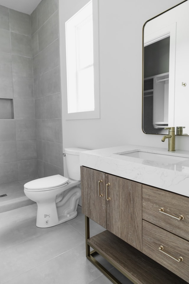 bathroom with a tile shower, tile patterned floors, vanity, and toilet