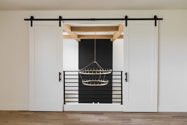 room details featuring beam ceiling, a barn door, and hardwood / wood-style flooring