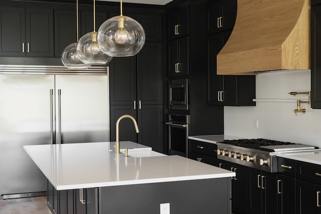 kitchen featuring a kitchen island with sink, sink, built in appliances, a kitchen bar, and custom range hood