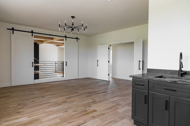 living room featuring light wood-type flooring, a barn door, a chandelier, and sink