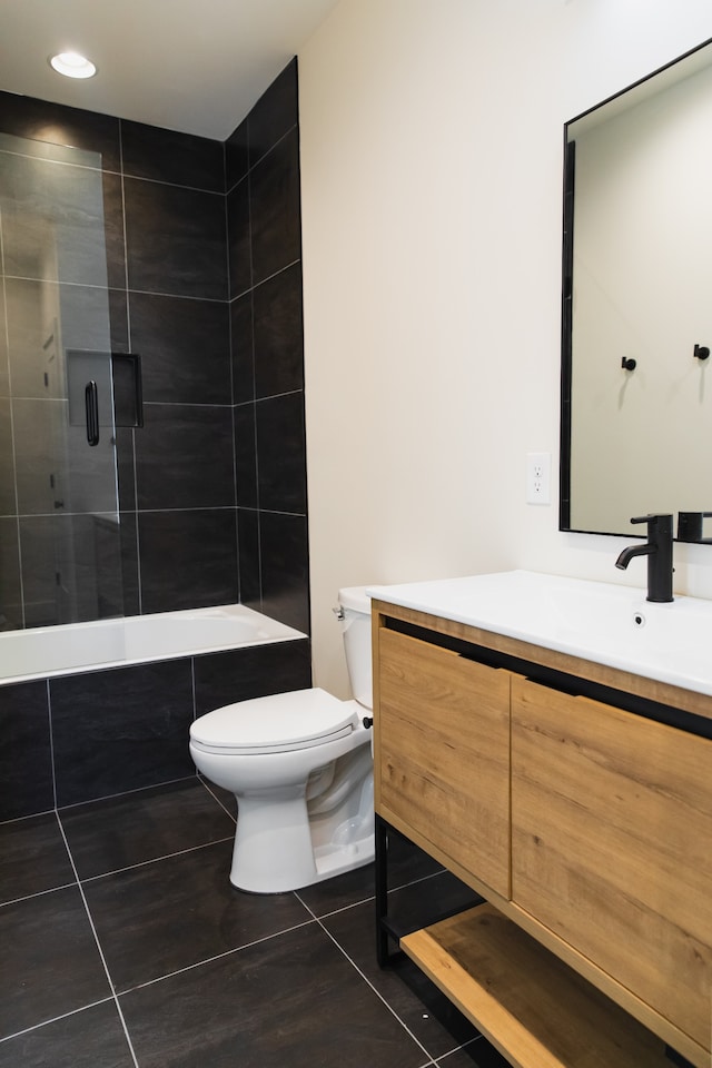 full bathroom with tile patterned flooring, vanity, tiled shower / bath combo, and toilet