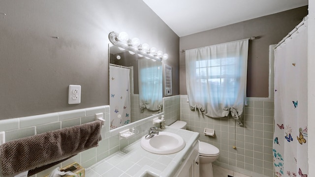 bathroom with vanity, toilet, tile walls, and curtained shower