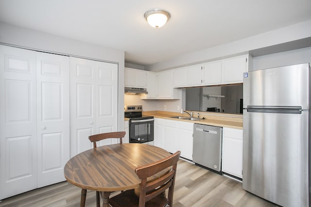 kitchen featuring white cabinets, light wood-type flooring, stainless steel appliances, and sink