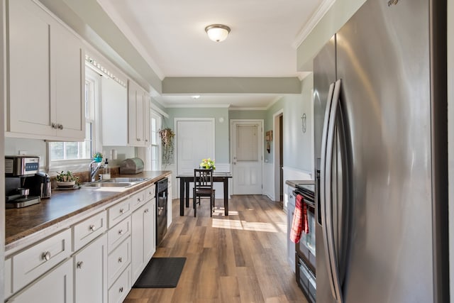 kitchen with sink, white cabinetry, light hardwood / wood-style flooring, ornamental molding, and stainless steel appliances