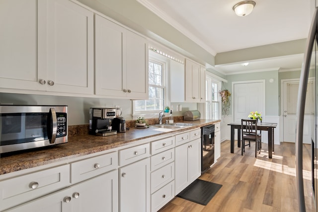 kitchen with light wood-type flooring, dishwasher, sink, and white cabinets