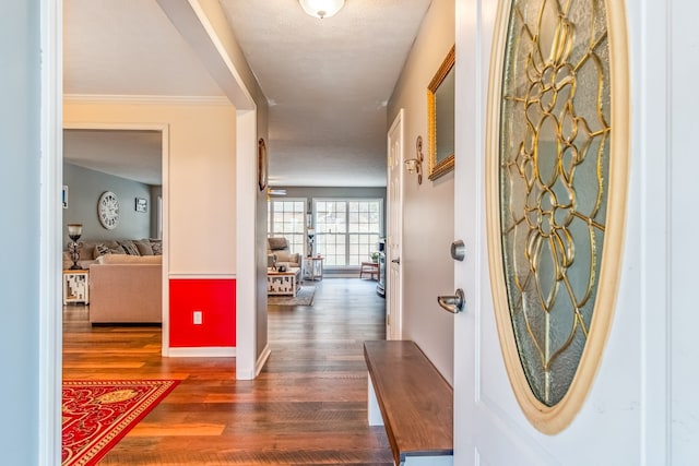 hallway with dark hardwood / wood-style flooring, a textured ceiling, and ornamental molding