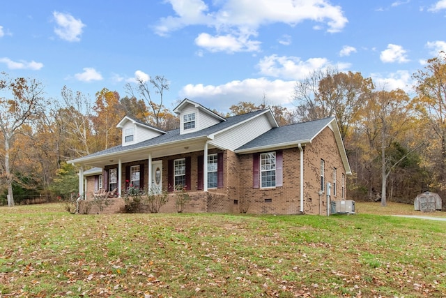 view of front of house with a storage unit, cooling unit, covered porch, and a front lawn