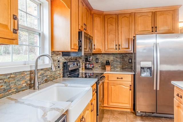 kitchen with sink, light stone counters, backsplash, light tile patterned floors, and appliances with stainless steel finishes