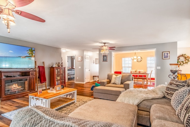 living room featuring ceiling fan with notable chandelier and wood-type flooring