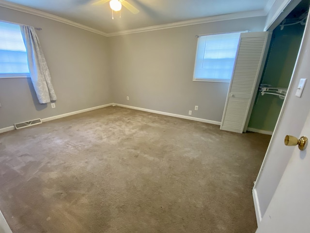 unfurnished bedroom featuring carpet flooring, a closet, ceiling fan, and crown molding