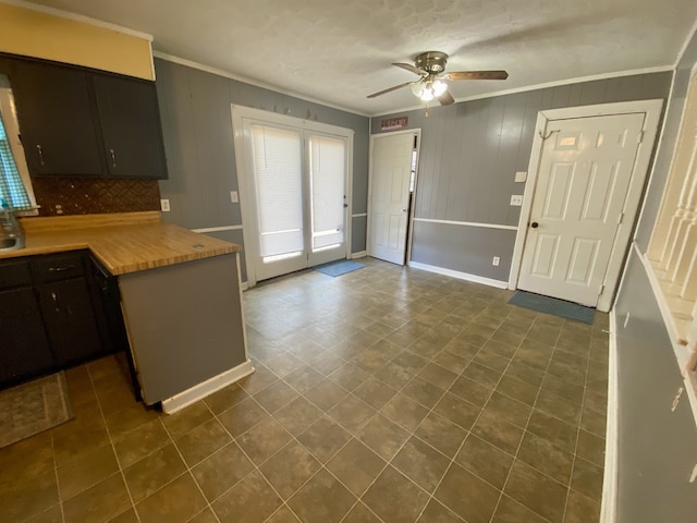 kitchen featuring tasteful backsplash, ornamental molding, ceiling fan, wooden walls, and butcher block counters