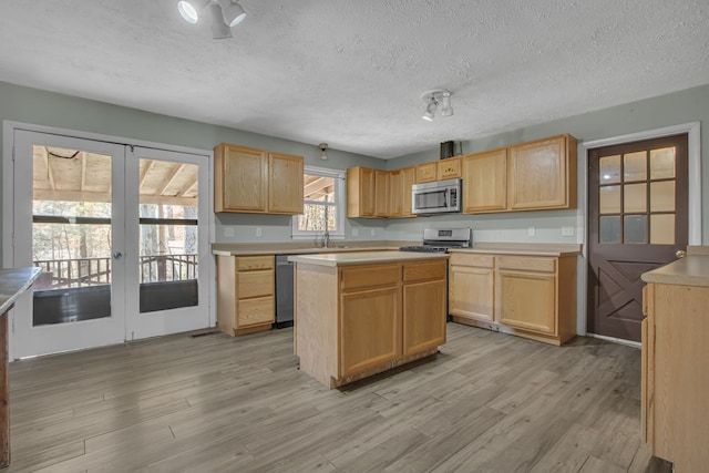 kitchen with appliances with stainless steel finishes, light brown cabinets, light hardwood / wood-style flooring, and french doors