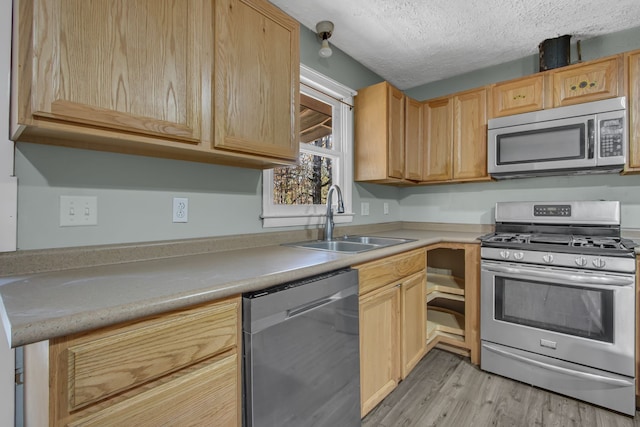 kitchen with sink, light brown cabinets, light hardwood / wood-style floors, a textured ceiling, and appliances with stainless steel finishes