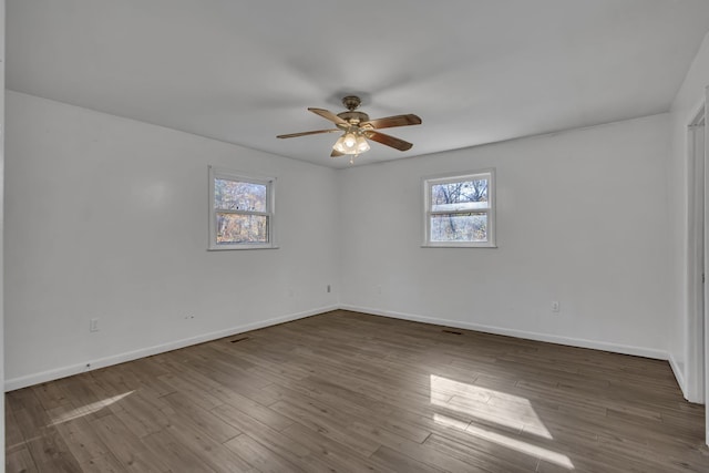 empty room with ceiling fan, dark hardwood / wood-style flooring, and a healthy amount of sunlight