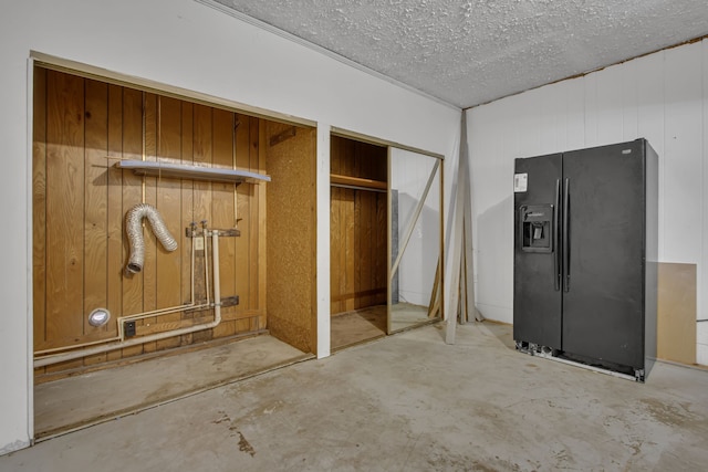 interior space with wood walls, a textured ceiling, and concrete floors