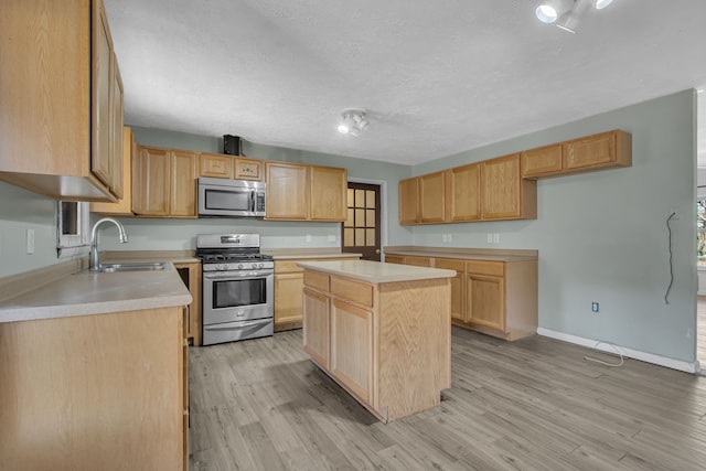 kitchen featuring appliances with stainless steel finishes, light brown cabinetry, sink, light hardwood / wood-style flooring, and a kitchen island