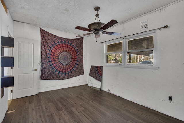 empty room featuring a textured ceiling, ceiling fan, and dark wood-type flooring