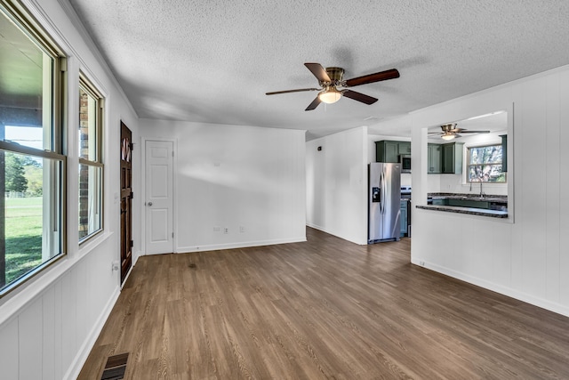 unfurnished living room featuring a textured ceiling, dark hardwood / wood-style flooring, and ceiling fan