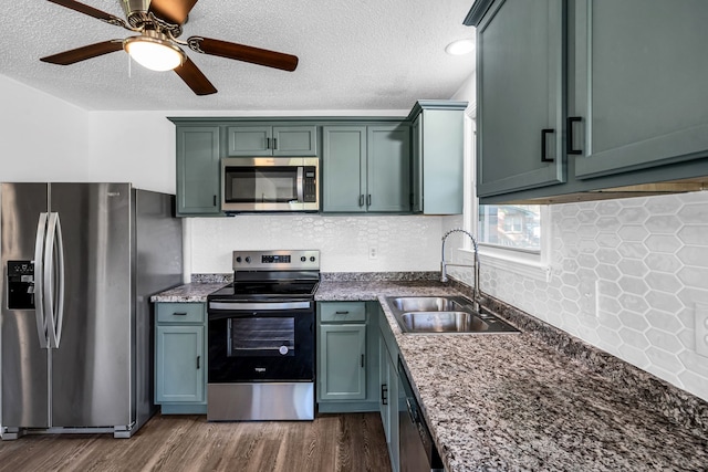 kitchen with dark wood-type flooring, stone counters, sink, a textured ceiling, and stainless steel appliances