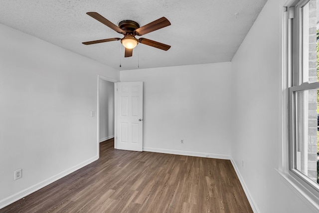 spare room featuring ceiling fan, plenty of natural light, dark wood-type flooring, and a textured ceiling