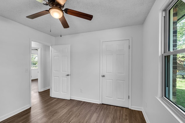 unfurnished bedroom with a textured ceiling, ceiling fan, and dark wood-type flooring