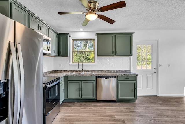 kitchen featuring hardwood / wood-style floors, appliances with stainless steel finishes, green cabinets, and sink