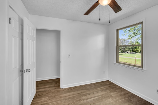 empty room with hardwood / wood-style floors, ceiling fan, and a textured ceiling