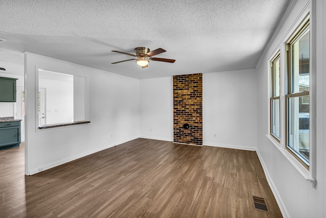 unfurnished living room featuring a textured ceiling, a wealth of natural light, ceiling fan, and dark hardwood / wood-style floors