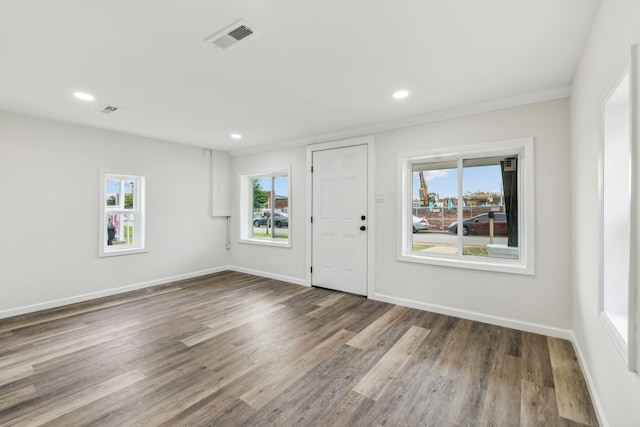 entrance foyer featuring dark hardwood / wood-style floors, a wealth of natural light, and crown molding