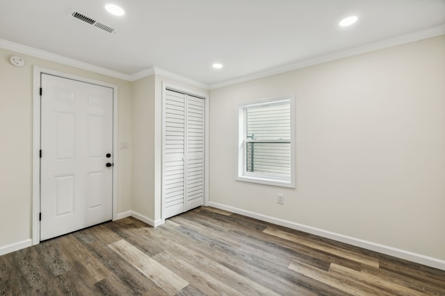 unfurnished bedroom with hardwood / wood-style flooring, a closet, and ornamental molding