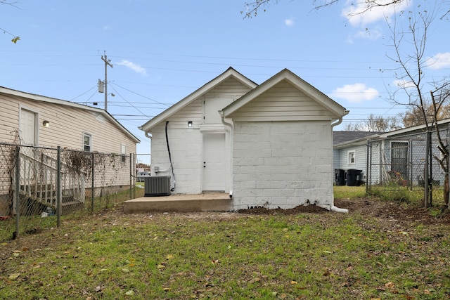 rear view of property featuring a lawn and central air condition unit